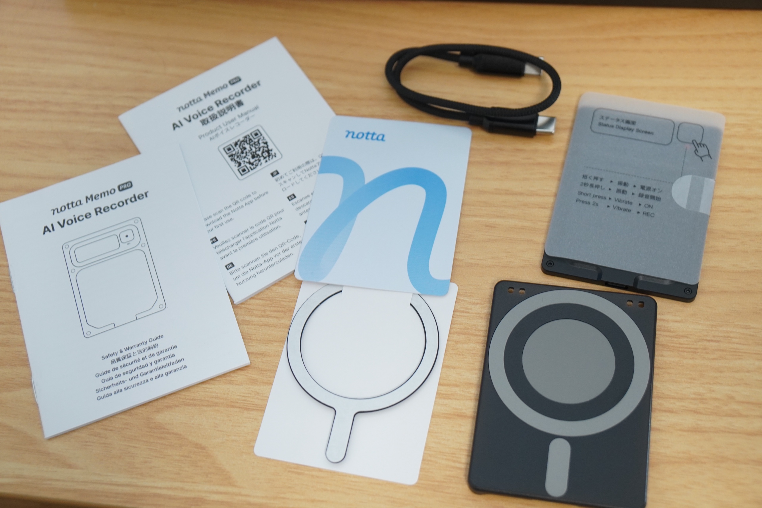 Notta Memo Proの同梱物。取扱説明書、品質保証の冊子、USB-Cケーブル、スマートフォンに貼る金属リング、MagSafe対応のケース、本体