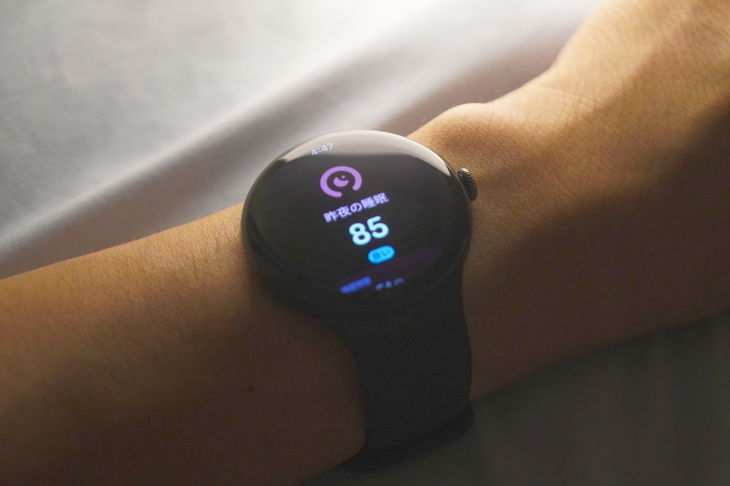 薄暗い寝室で腕に着けた Pixel Watch 5。画面に昨夜の睡眠スコアが表示されている