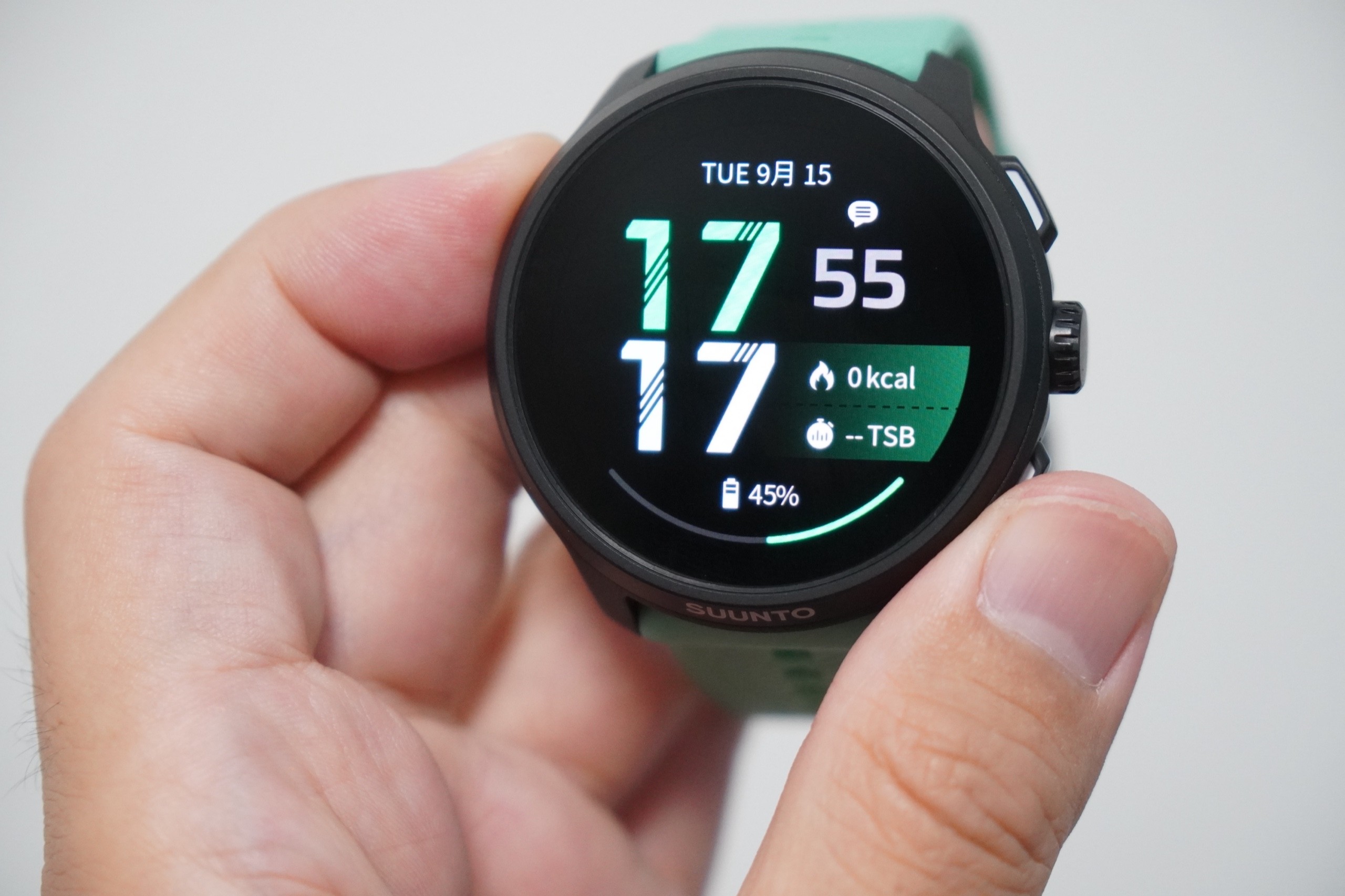 Suunto Run 2を手に持ち、1.32インチAMOLEDの文字盤を正面から見たところ。時刻と消費カロリー、バッテリー残量が表示されている