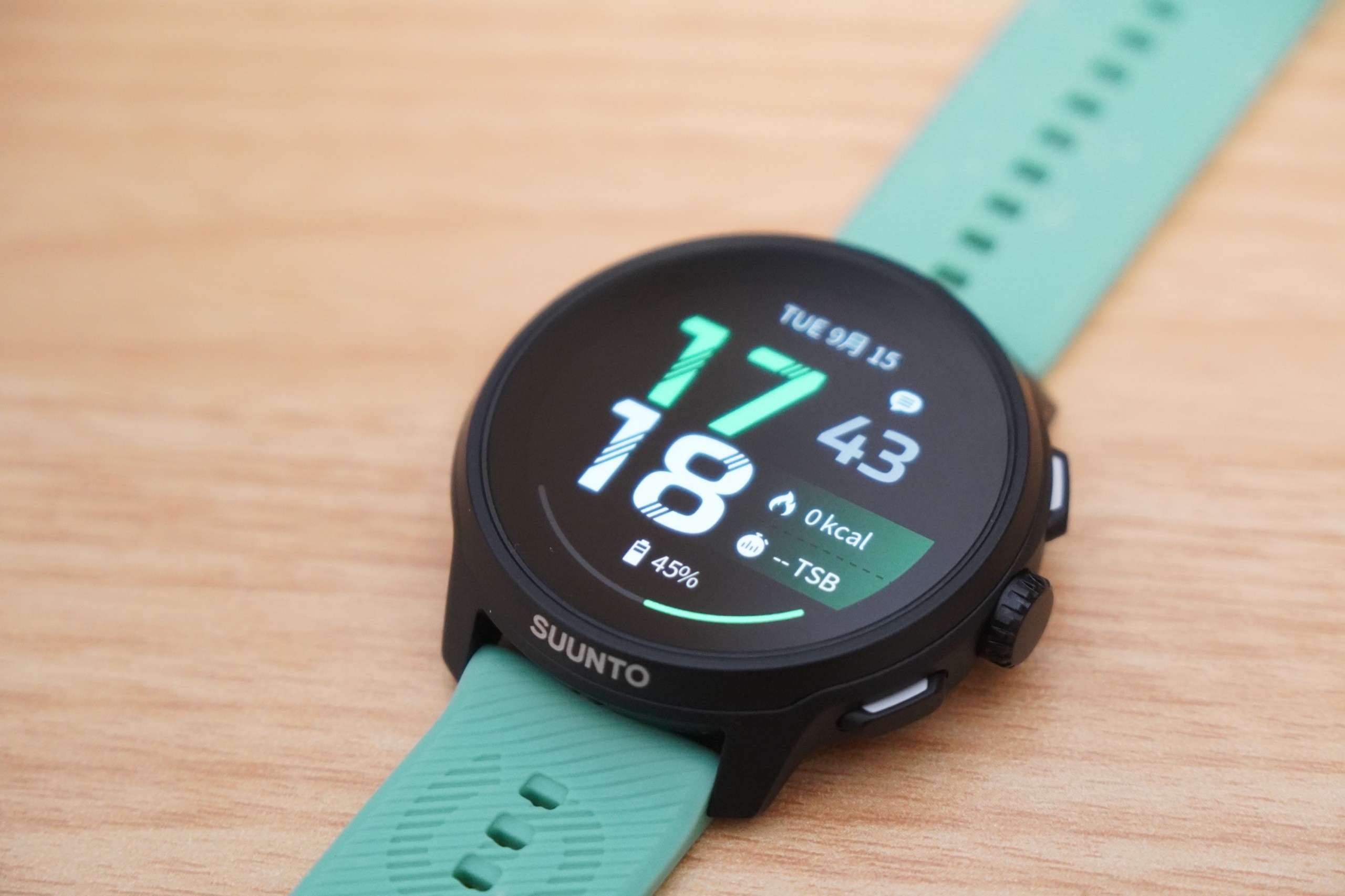 Suunto Run 2の本体とミントグリーンのシリコンストラップを広げて木のテーブルに置いたところ