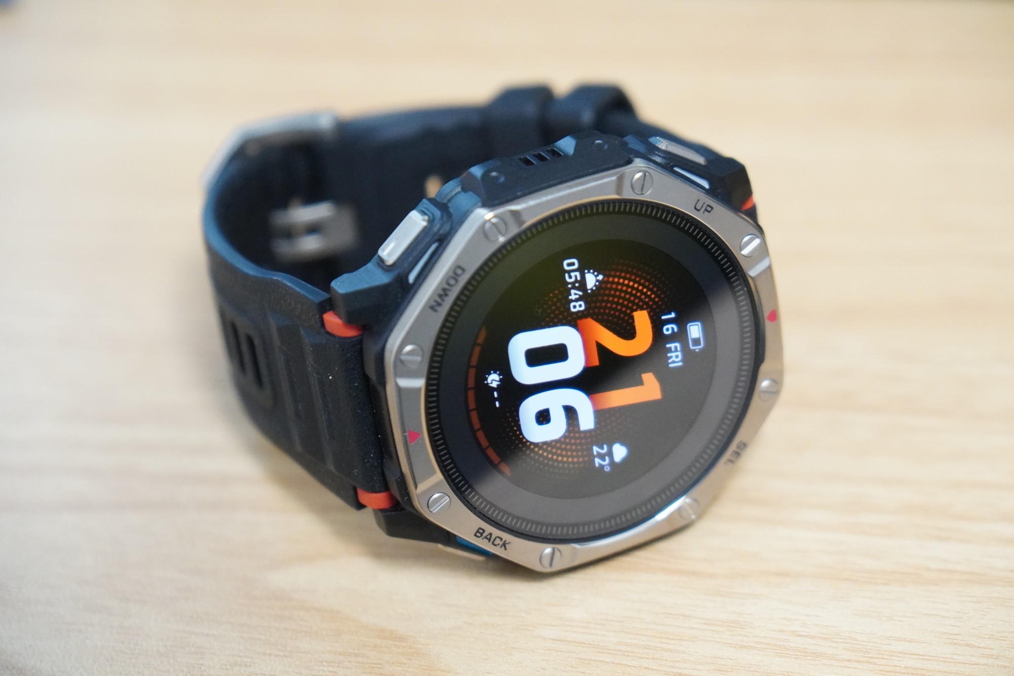 机の上に置いたAmazfit T-Rex Dual Solar。チタンのベゼルと4つのボタン、21時06分を表示したカラーの文字盤が写っている