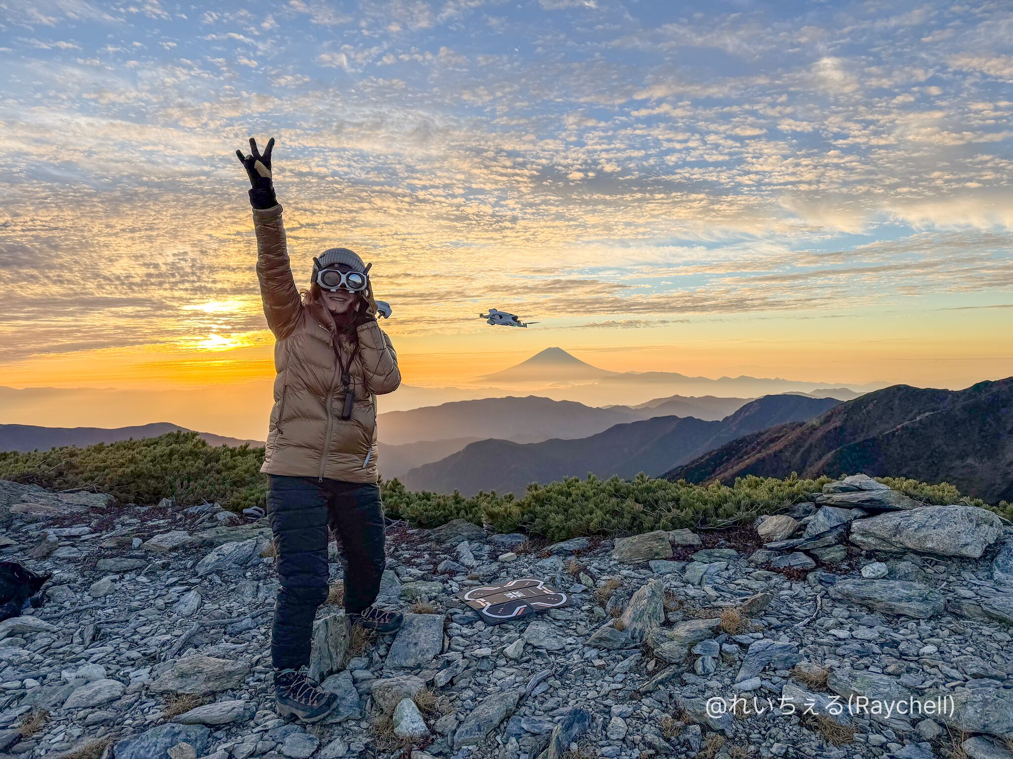 夕焼けの山頂でVisionゴーグルを着けた人と、その横を飛ぶAntigravity A1。遠くに富士山が見える(撮影:@れいちぇる(Raychell))