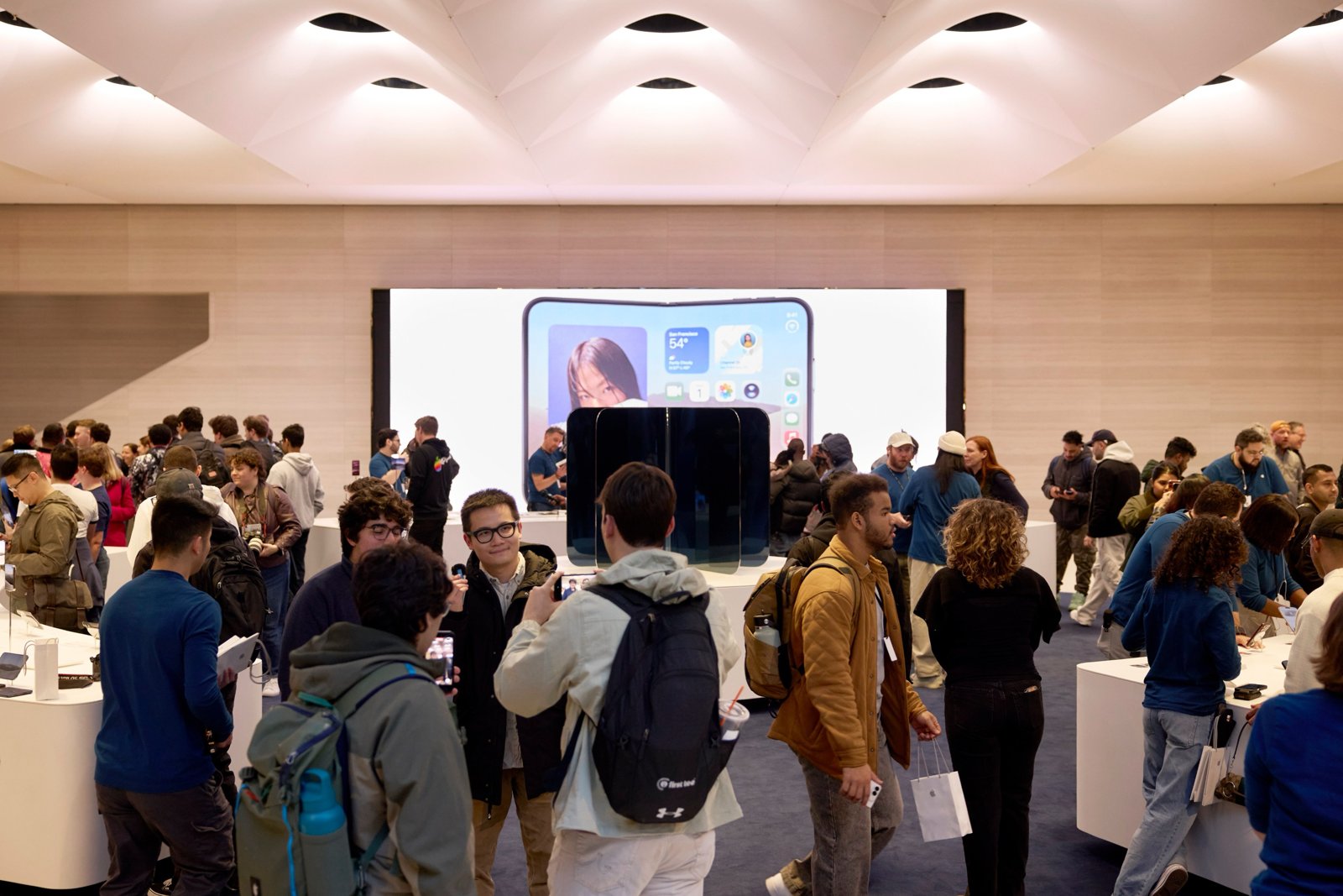 大きな画面にiPhone Duoが映るApple Fifth Avenueの店内とお客様