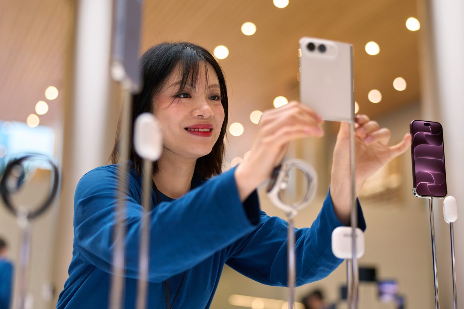Apple Jing'anでスタッフがiPhone Duoの展示機を手に取って見せているところ