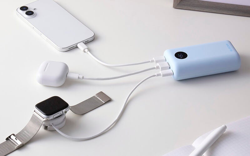 ブルーの8,000mAhモデルの3つのポートに、スマートフォン、ワイヤレスイヤホンのケース、スマートウォッチの充電器をつないで充電しているところ