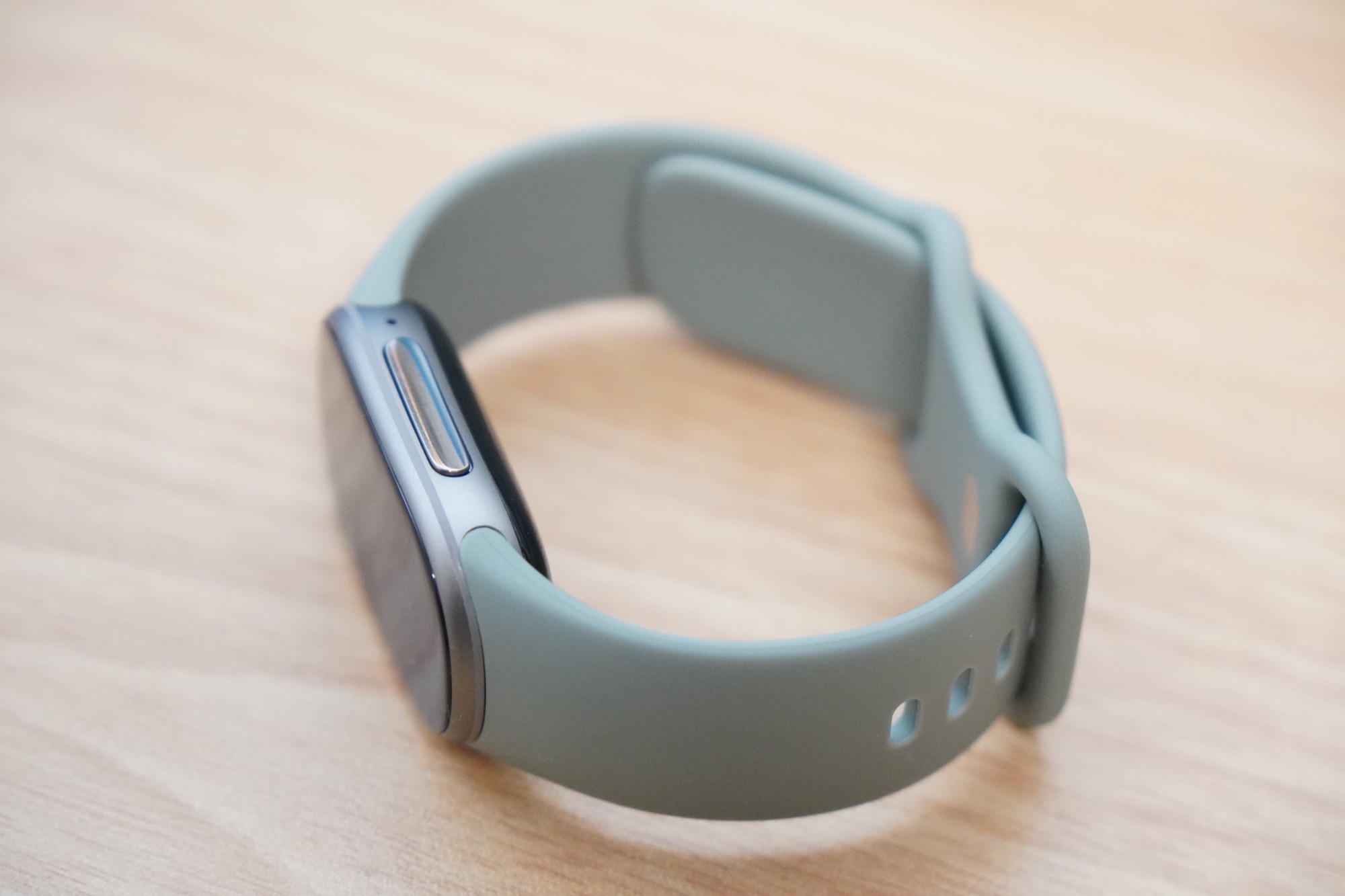Google Fitbit Edgeの側面。金属のケースに細長いサイドボタンがあり、淡いグリーンのバンドが付いている