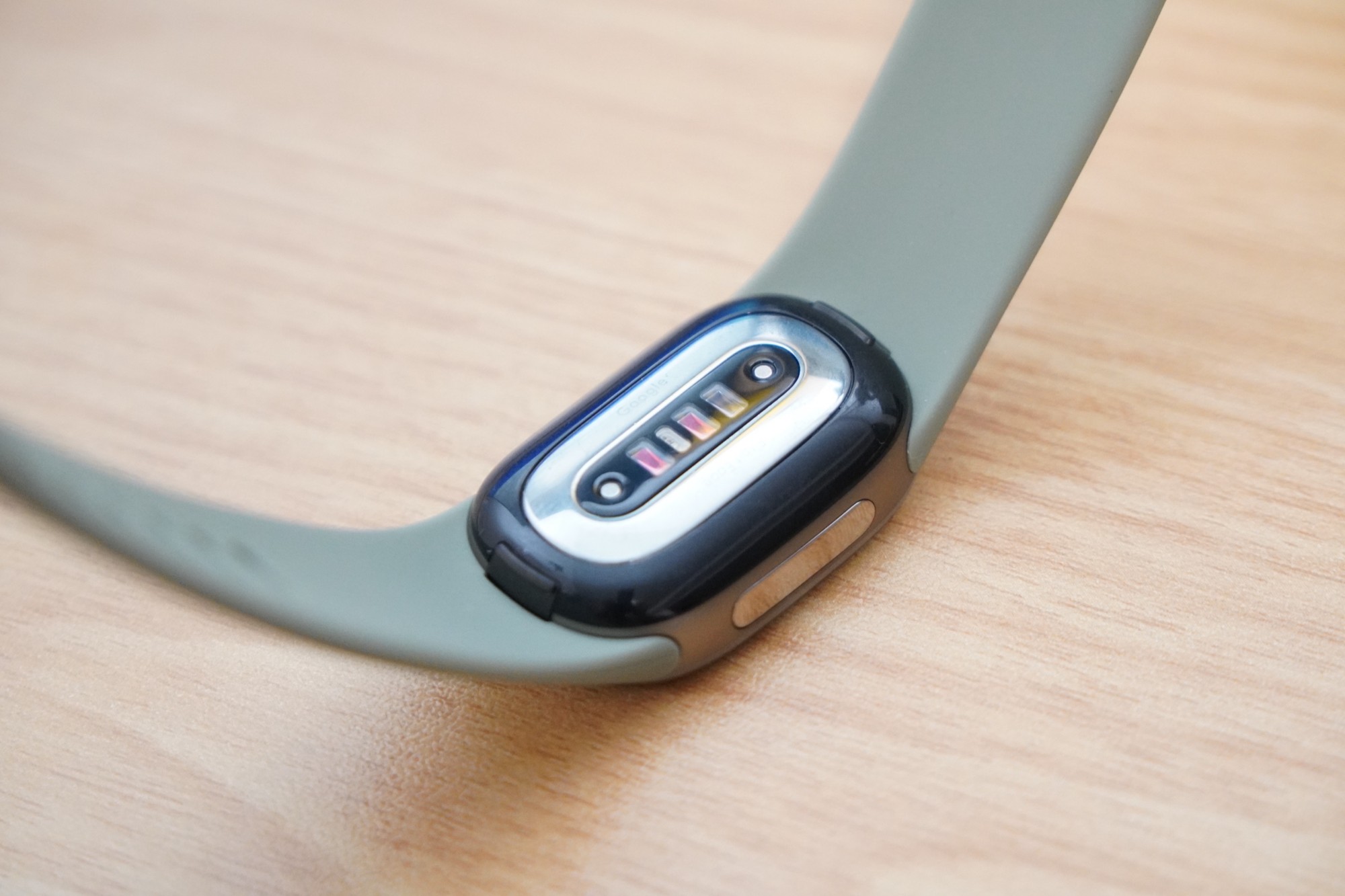 Google Fitbit Edgeの裏面。黒い部分の中央に金属の板があり、センサーの窓が横に並んでいる
