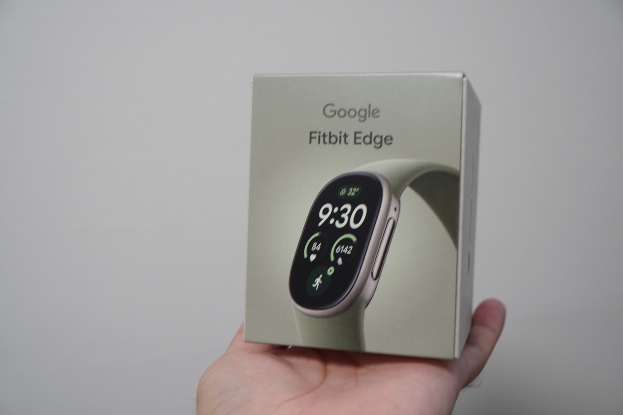 手のひらに載せたGoogle Fitbit Edgeの箱。正面にGoogle Fitbit Edgeの文字と本体の写真がある