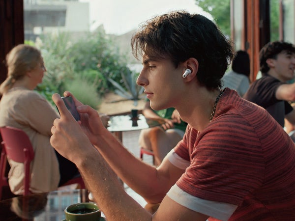 HUAWEI FreeBuds Neoを耳に着けて、スマートフォンでゲームをしている男性