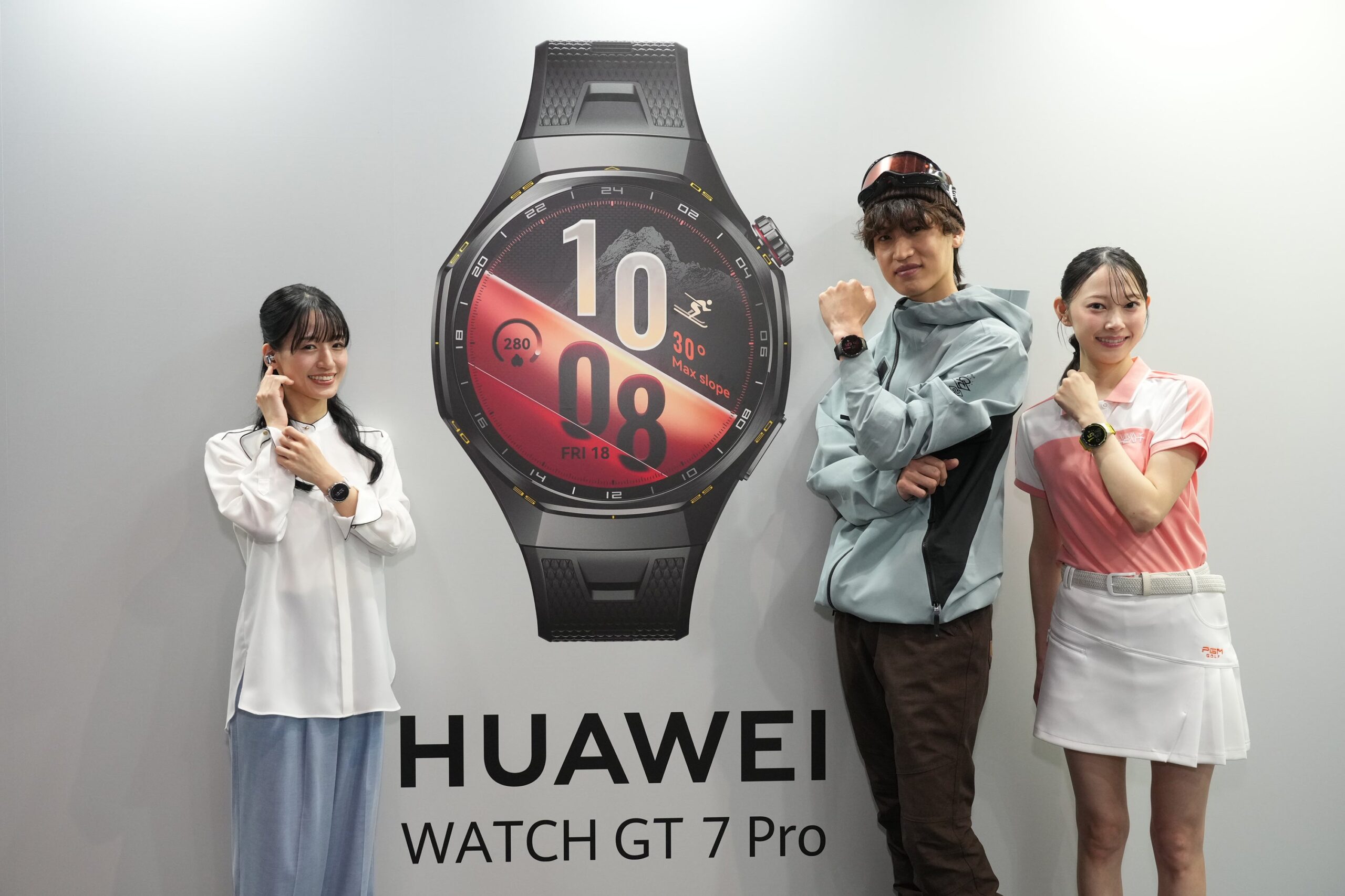 発表会のタッチアンドトライ会場で、HUAWEI WATCH GT 7 Proの大きなパネルの前でウォッチを着けて並ぶ3人