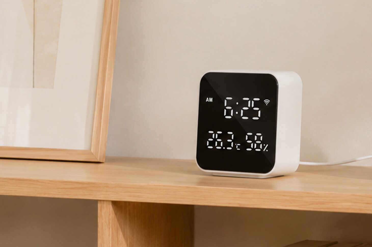 木の棚に置かれたHejhomeの6-in-1 スマートリモコンハブ。白い本体の黒い画面に時刻と温度・湿度が表示されている