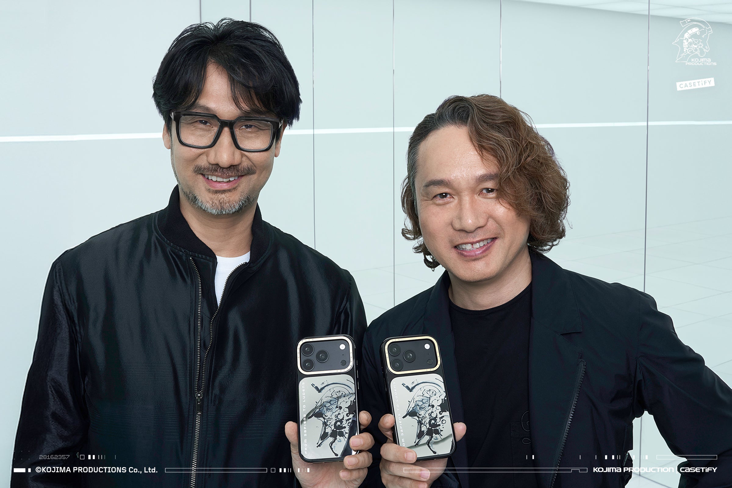 コラボのスマホケースを手に持つゲームクリエイターの小島秀夫氏とアートディレクターの新川洋司氏