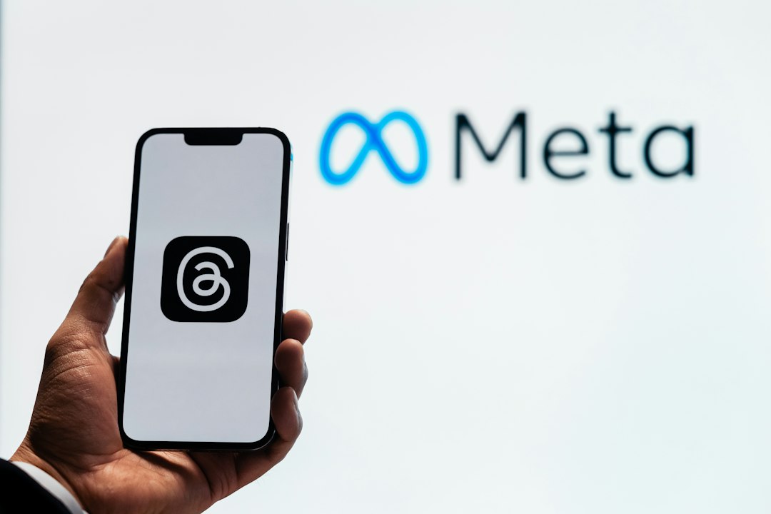 Metaのロゴの前でスマートフォンを掲げる手