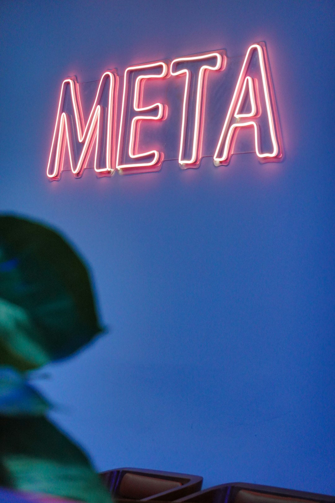 青い壁に光るMETAのネオンサイン