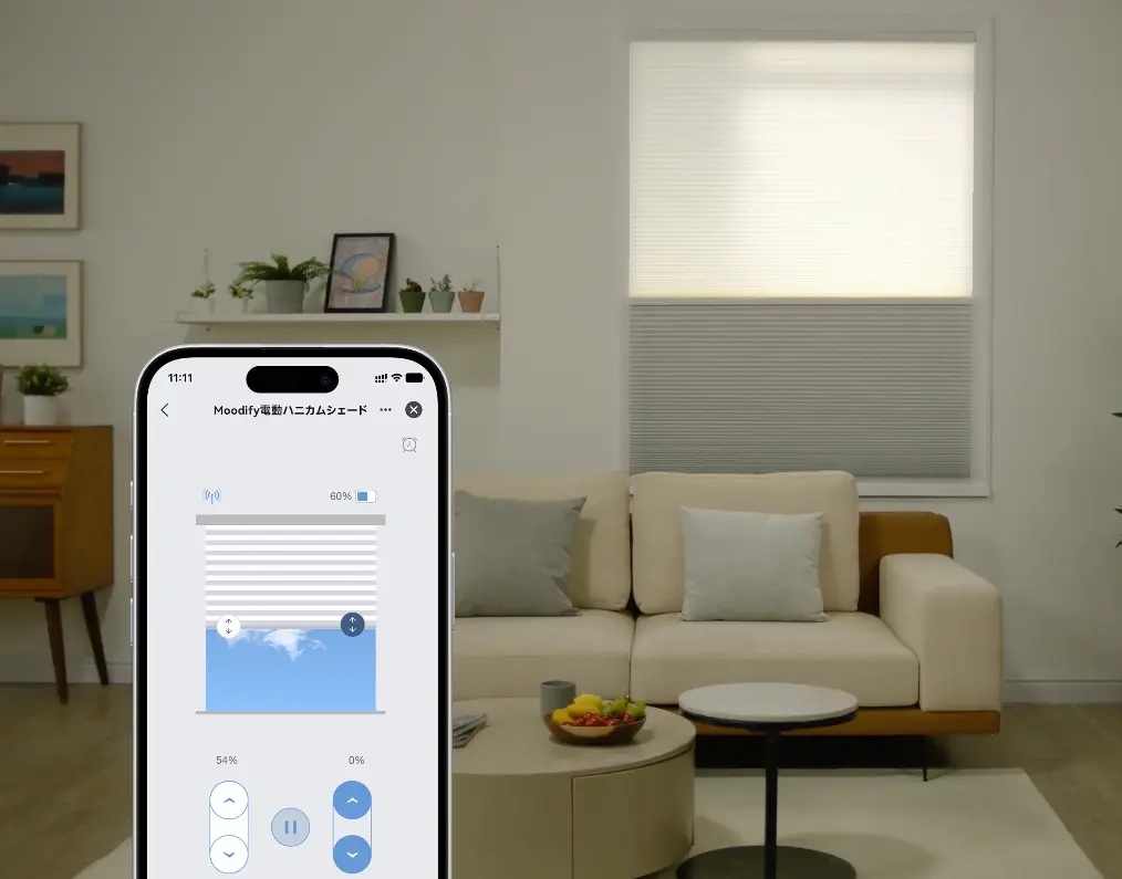 リビングの窓のMoodify電動ハニカムシェードと、開き具合を操作するスマートフォンアプリの画面