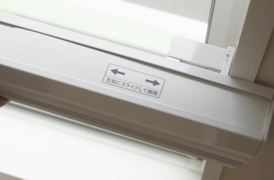 窓枠の正面に突っ張って固定するMoodify電動ハニカムシェードの取付部分。左右にスライドして開閉する表示がある