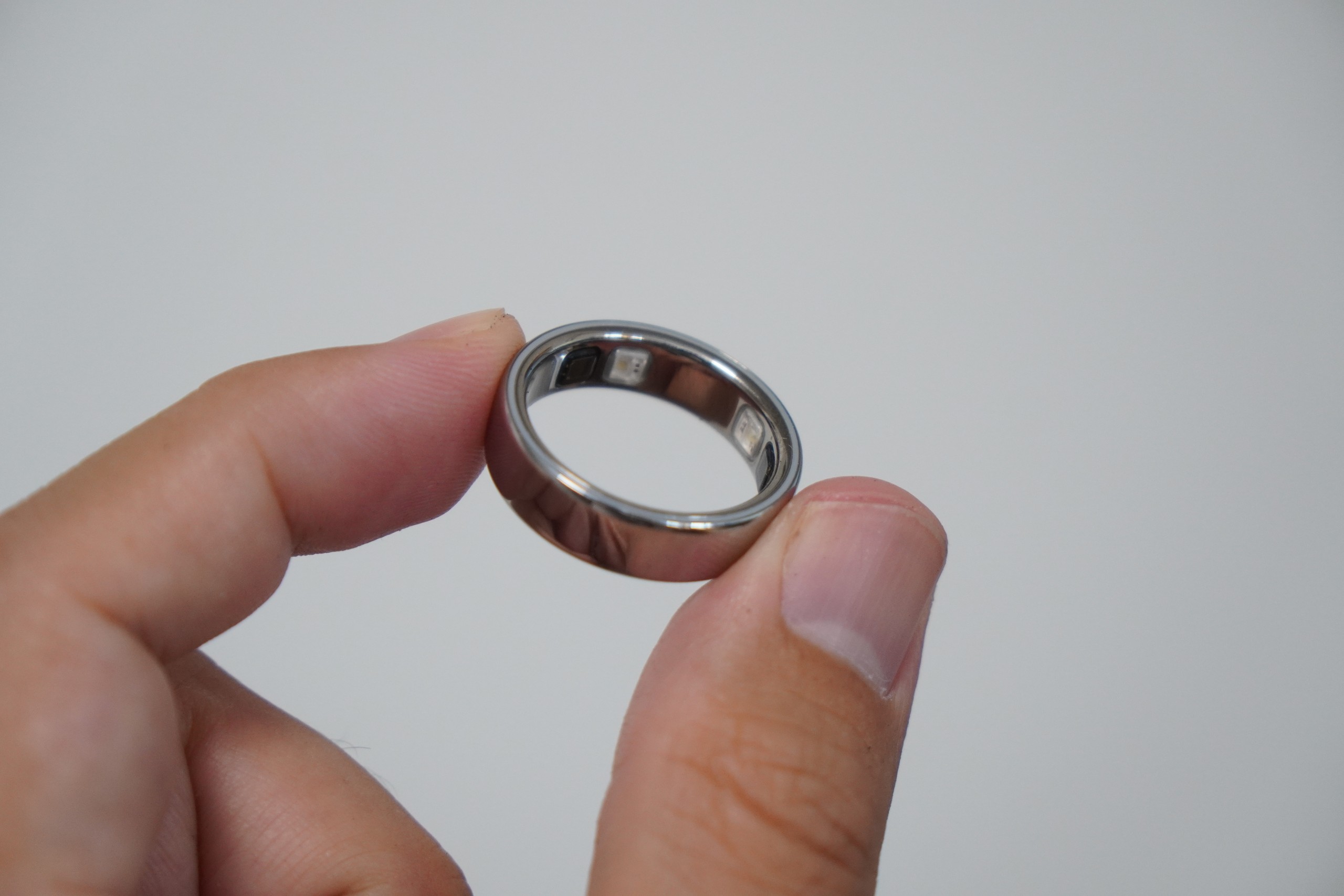 指でつまんだOura Ring 5の内側。センサーの窓が並んでいる