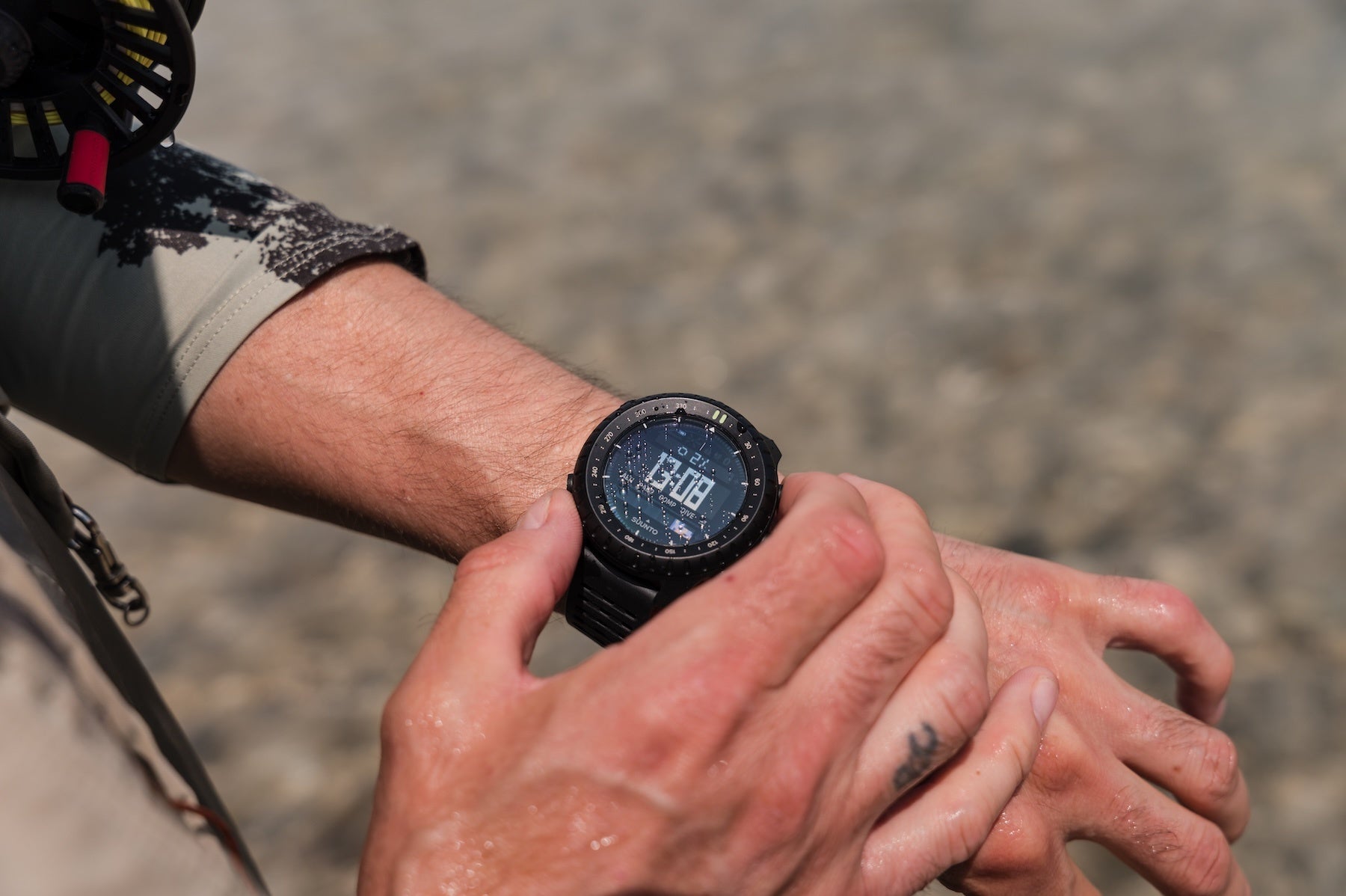 川辺で手首のSuunto Core 2を確認する手元。高度計・気圧計・コンパスをウォッチ単体で使える
