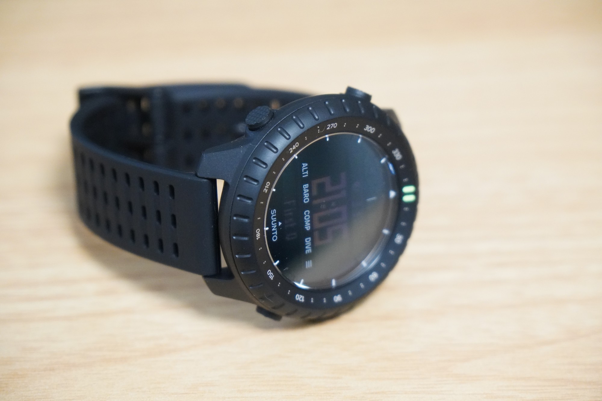 机の上に置いたSuunto Core 2。方位の目盛りが入ったベゼルと、時刻を表示した液晶の画面、左側のボタンが写っている