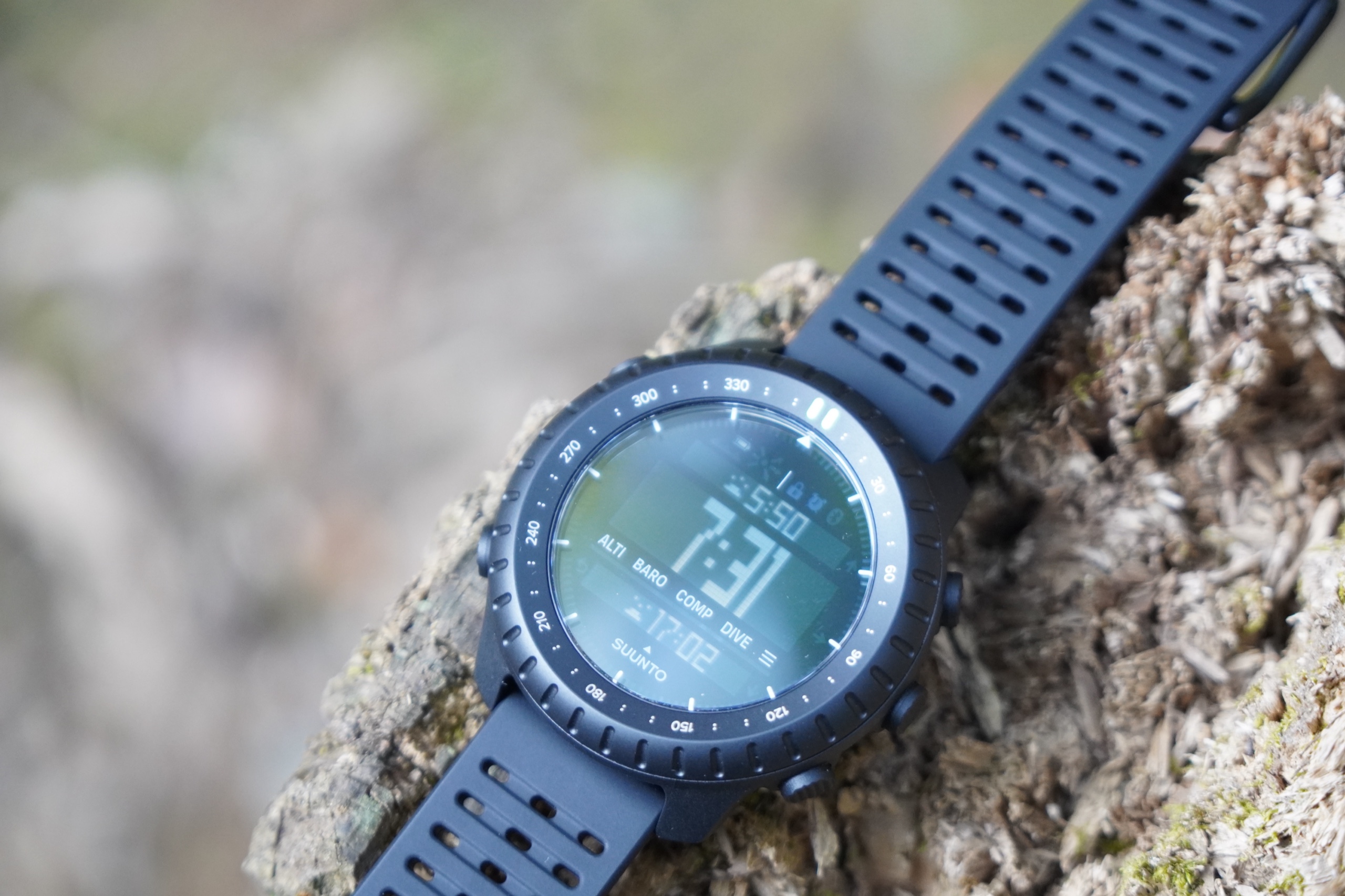切り株の上に置いたSuunto Core 2の時計画面。上段に5:50、下段に17:02と表示されている