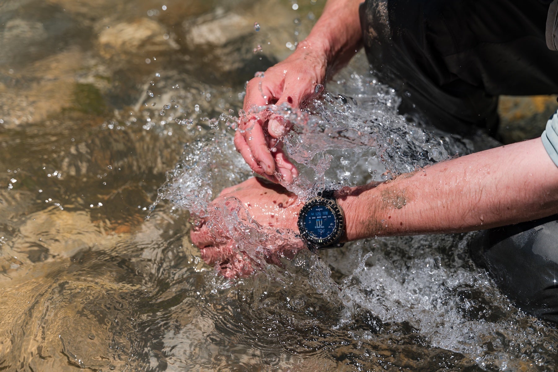 Suunto Core 2を着けたまま川の水で手を洗う様子。防水性能は10ATM