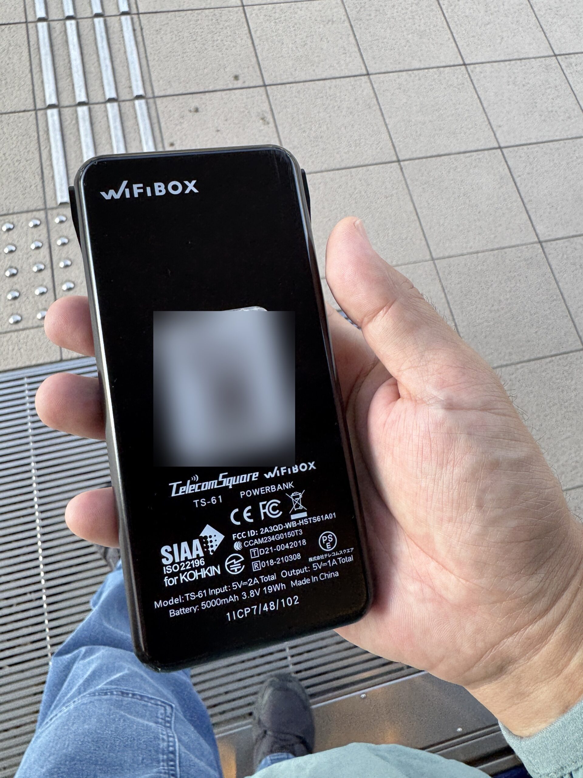 手に持ったWiFiBOXの端末の裏面。型番TS-61、POWERBANK、バッテリー5000mAhの表記がある