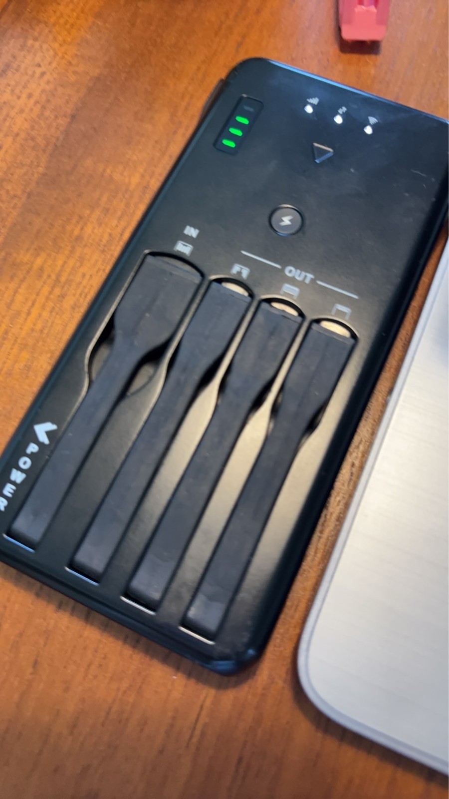 机に置いたWiFiBOXの端末の表面。4本のケーブルが本体に収まり、INとOUTの表記がある