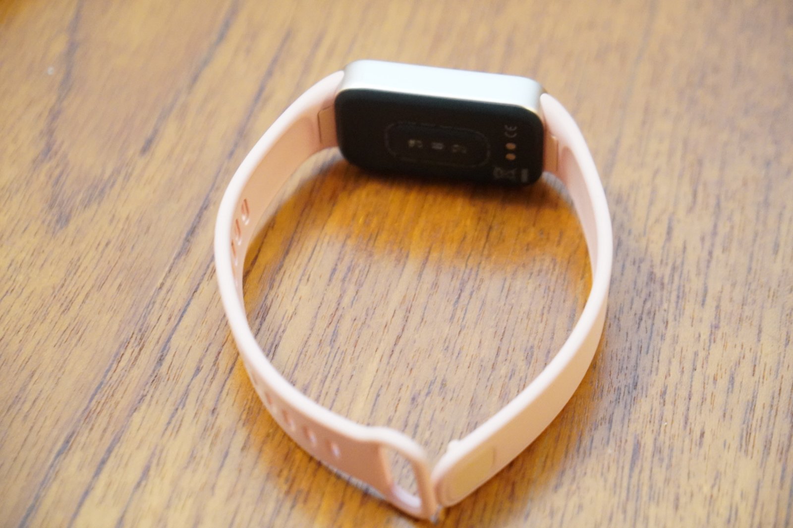 ストラップを輪にして置いたXiaomi Smart Band 11 Activeの裏面。中央に心拍センサー、右側に磁気充電用の2つの接点が並んでいる