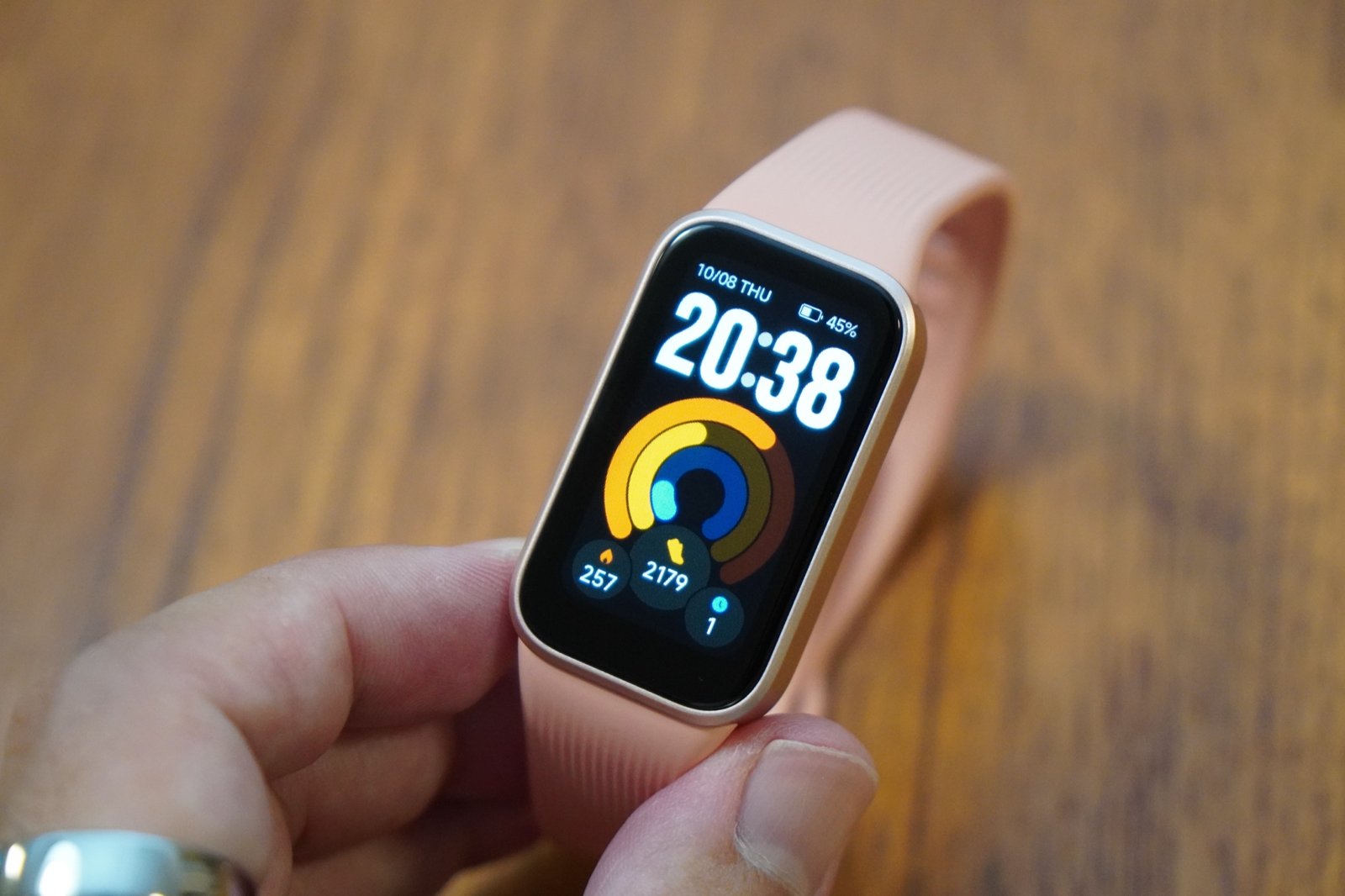 手に持ったXiaomi Smart Band 11 Active。1.47インチの画面に20時38分の時刻と3色のリング、歩数などが表示されている