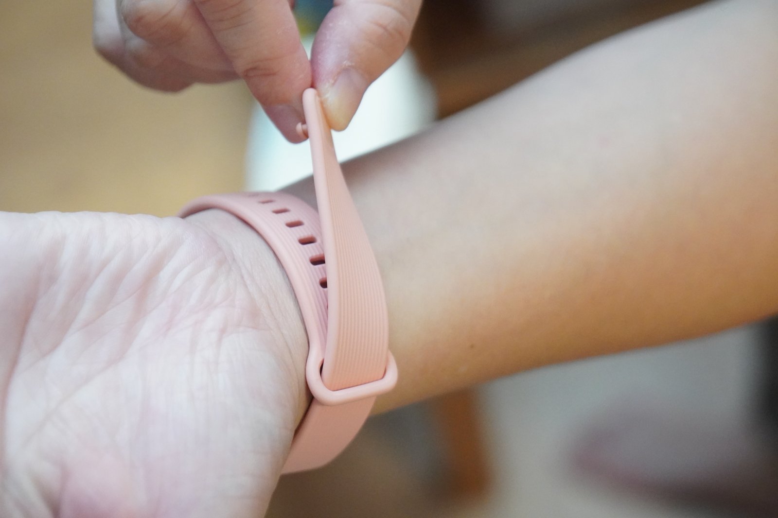 Xiaomi Smart Band 11 Activeのストラップを手首に巻き、先端のピンを穴に差し込もうとしているところ