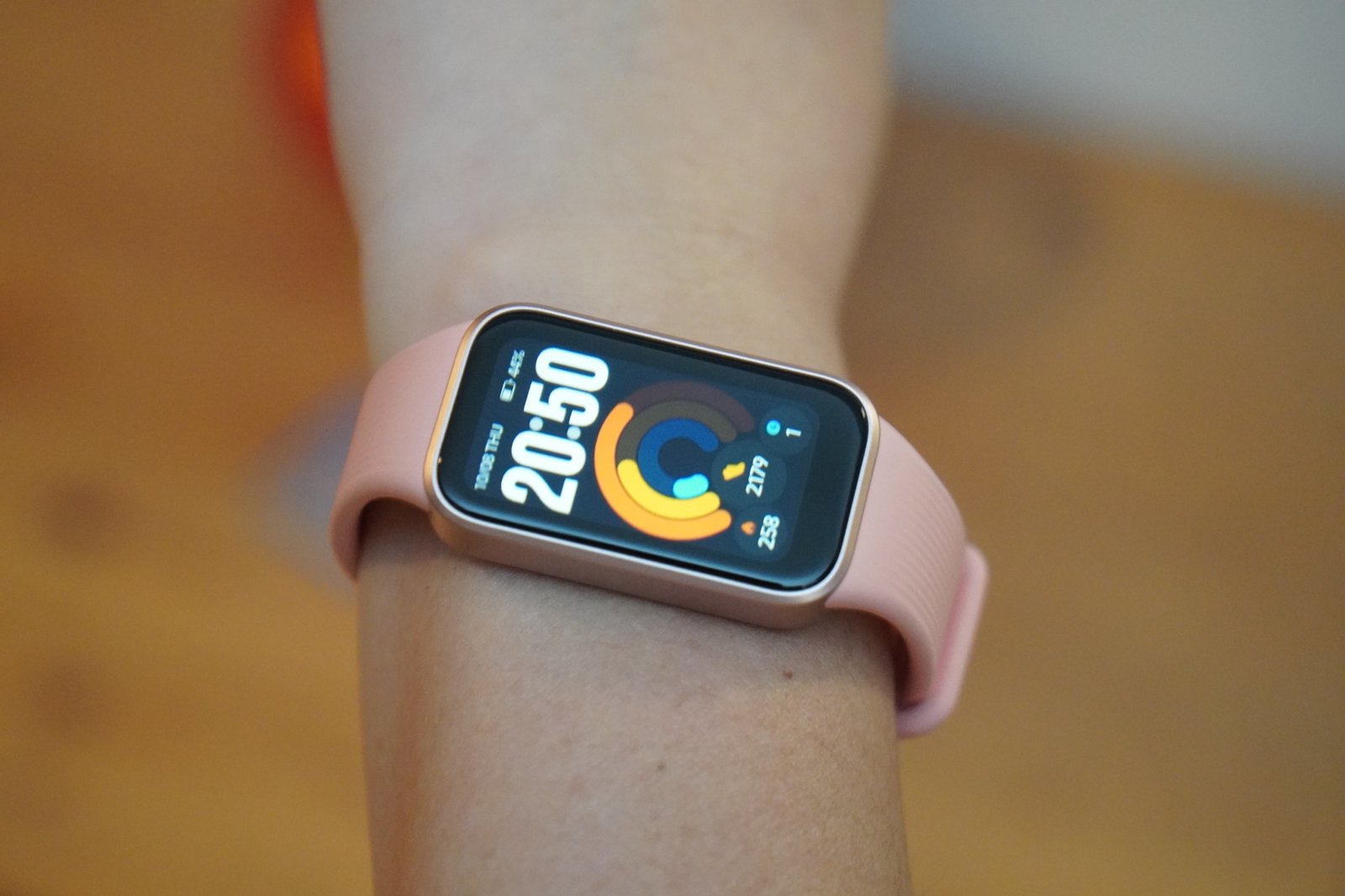 手首に着けたXiaomi Smart Band 11 Active。ピンクのストラップと淡いゴールドのフレームに、20時50分の画面が光っている