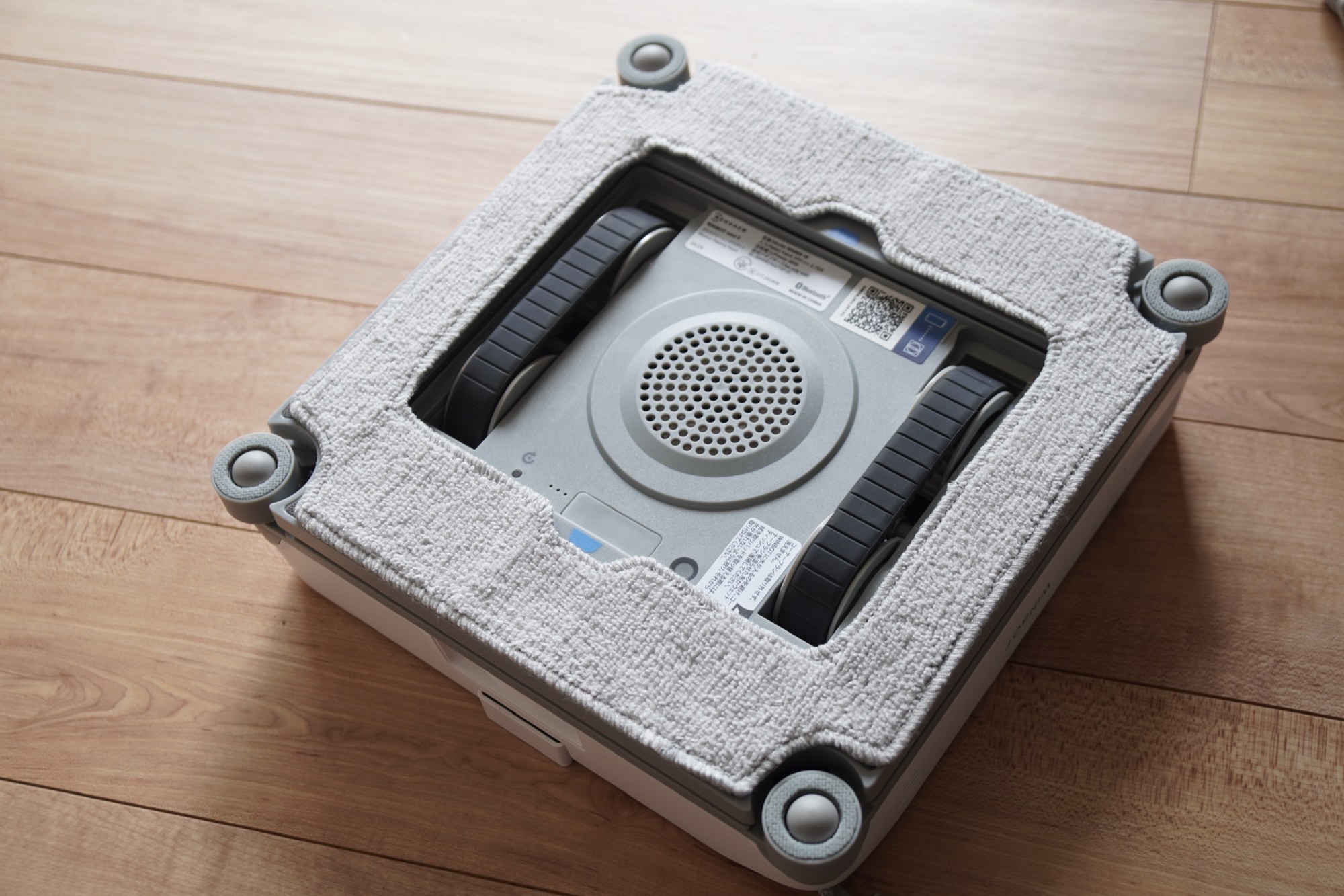 WINBOT mini 2の裏面。ワイピングパッドを取り付けた状態で、四隅に丸いパーツ、中央に吸着用のファンと2本の走行ベルトがある