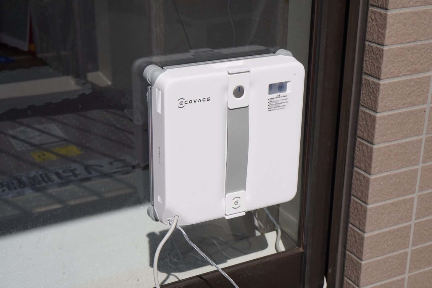 窓ガラスに吸着して清掃中のECOVACS WINBOT mini 2を正面から撮ったところ