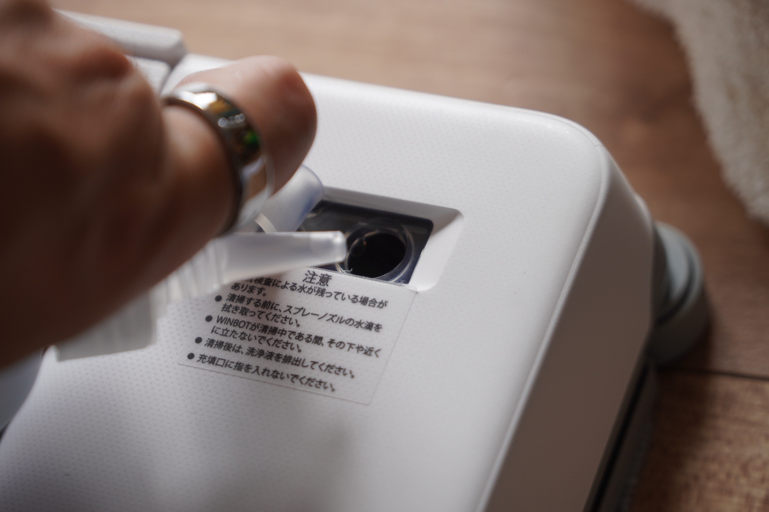 WINBOT mini 2の注ぎ口に付属の洗浄液を入れているところ